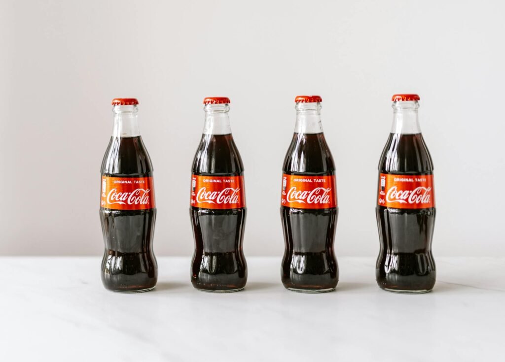 Glass bottles of cola on white table